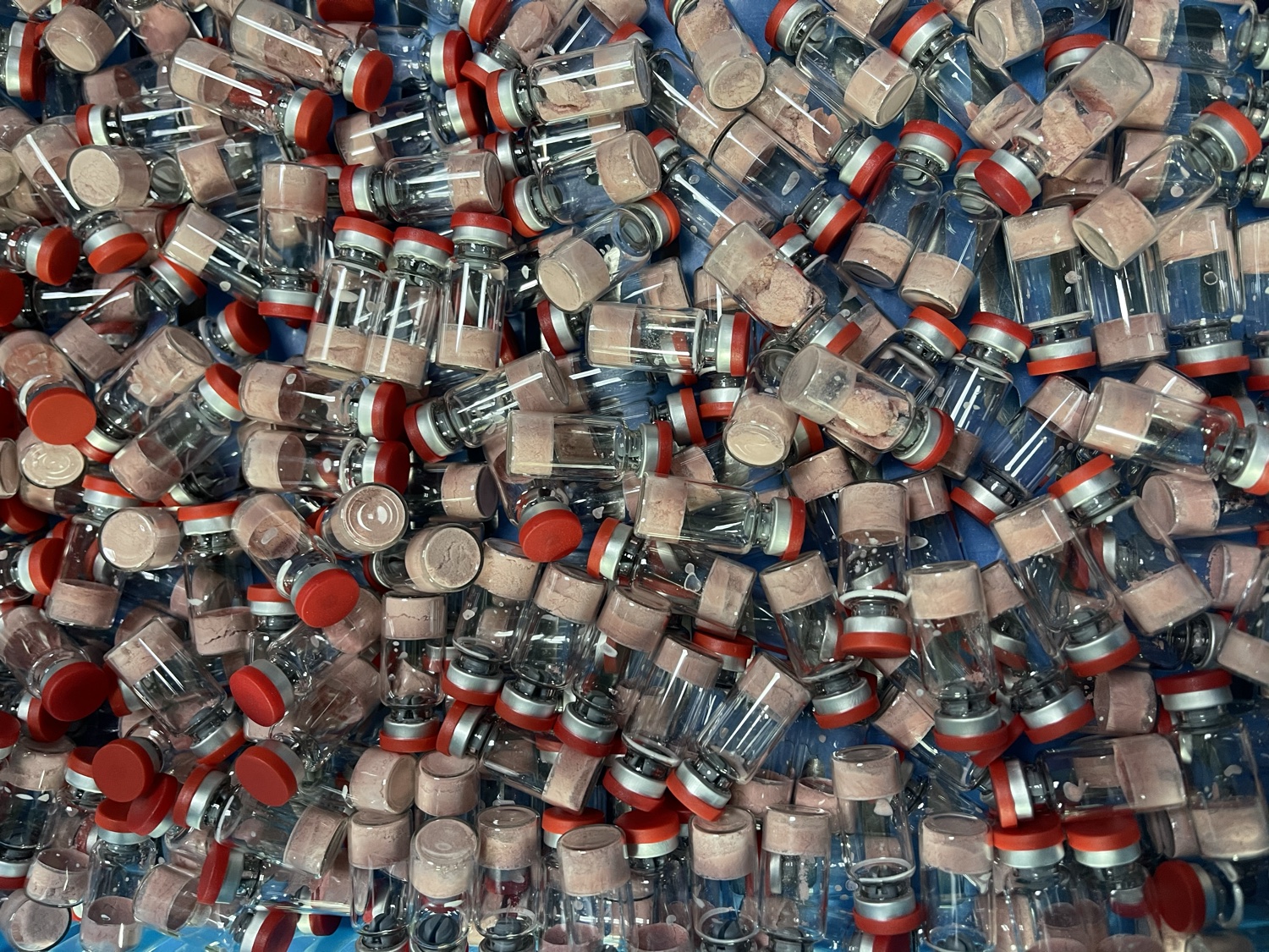 A large batch of clear peptide vials with red caps